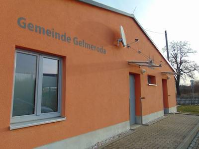 Das Bild zeigt die Außenfassade des Jugendzimmers Gelmeroda. Die Fassade ist orange und es ist der Schriftzug Gelmeroda sowie die Tür zu sehen.
