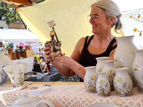 Eine Handwerkerin zeigt eine Figur aus Ton an ihrem Stand auf dem Weimarer Töpfermarkt