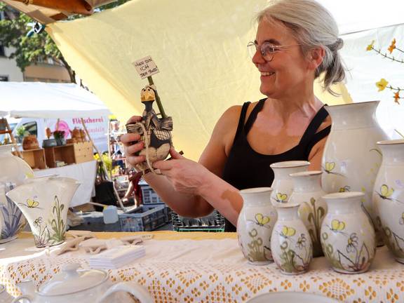 Eine Handwerkerin zeigt eine Figur aus Ton an ihrem Stand auf dem Weimarer Töpfermarkt