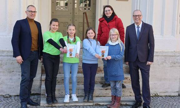 Oberbürgermeister Peter Kleine, Frida, Rebekka, Olivia, Luna, Kinder- und Jugendbeauftragte Sina Solaß und Bürgermeister Ralf Kirsten zeigen den Rathausführer