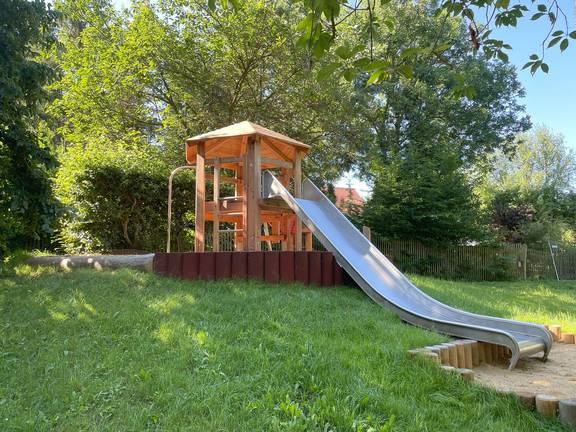 Spielanlage mit Rutsche und Rutschstange am Hang