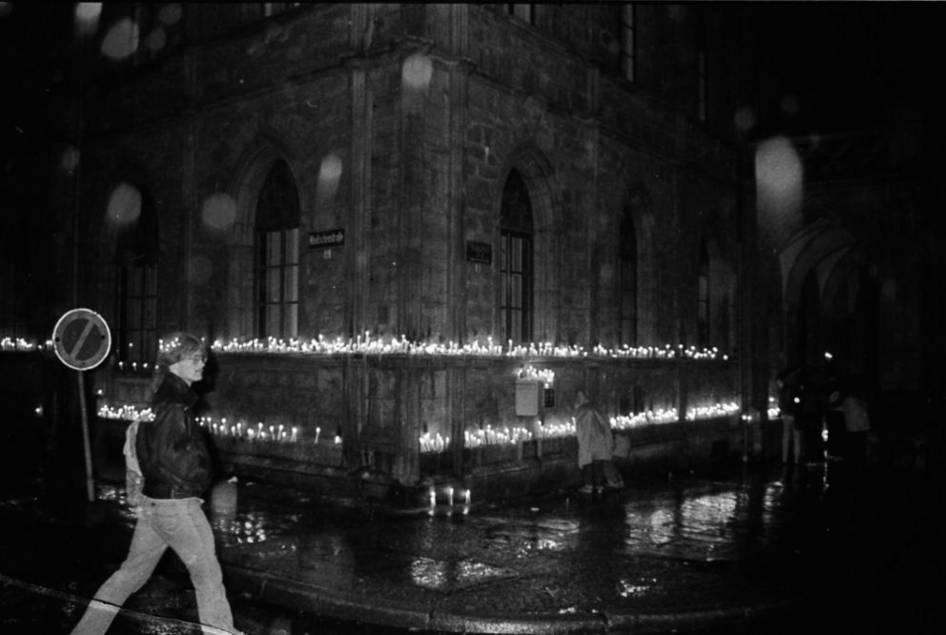 Gerade an den Gebäuden, die als Zentren der Macht galten, wurden während der friedlichen Revolution immer wieder Kerzen als Symbol der Gewaltlosigkeit aufgestellt. Die Aufnahme des Rathauses in Dunkelheit und Regen entstand im Spätherbst 1989.
