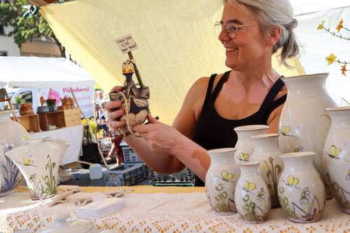Eine Handwerkerin zeigt eine Figur aus Ton an ihrem Stand auf dem Weimarer Töpfermarkt