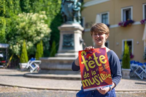 Fachreferentin für Musik, Anna-Lena Öhmann mit dem Plakat der diesjährigen "Fête de la Musique" vor dem Donndorfbrunnen. Auch der Platz an der Ecke Geleitstraße/Rittergasse wird wieder bespielt.
