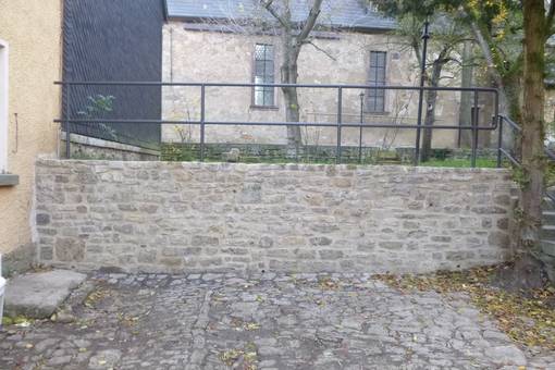 Im Zuge der Arbeiten wurden die Fundamente der historischen Natursteinmauer erneuert, das Mauerwerk wieder fachgerecht errichtet sowie eine Absturzsicherung oberhalb der Mauerkrone neu installiert.