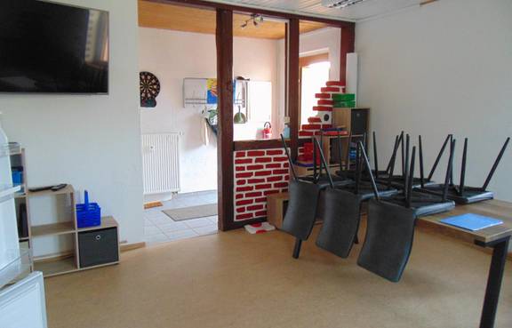 Das Bild zeigt das Jugendzimmer Gelmeroda von innen mit Blickrichtung zur Eingangstür. Fernseher , Balken und ein Regal sind zu sehen.