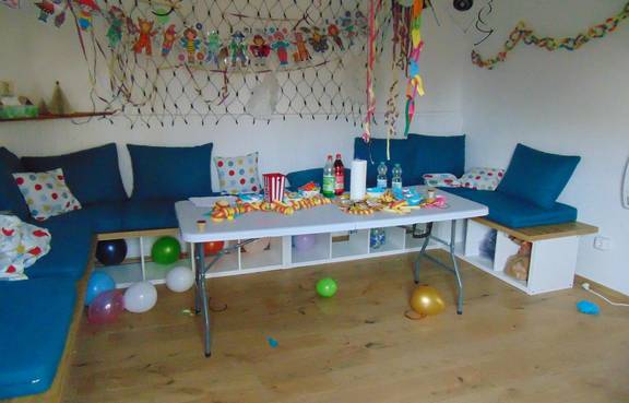 Auf dem Bild ist das Jugendzimmer Possendorf von innen zu sehen. Es ist bunt dekoriert wegen der Faschingsparty, Sitzbänke mit blauen Kissen sind zu sehen.