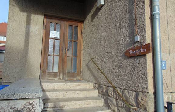 Auf dem Bild ist der Treppenaufgang zum Jugendzimmer Taubach zu sehen und das Schild mit der Aufschrift Mitmachgarten.