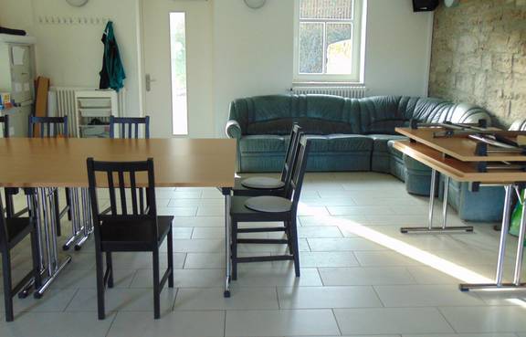 Auf dem Bild ist die Innenansicht des Jugendzimmers Süßenborn zu sehen, man kann ein Sofa und Stühle sehen.