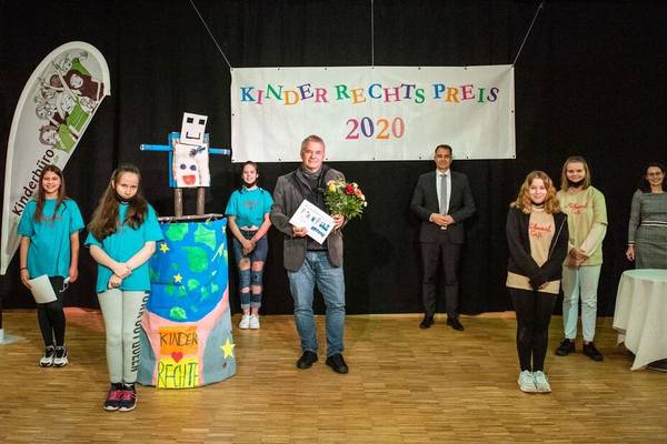 Die Kinderjury, der Oberbürgermeister Peter Kleine und die Kinder- und Jugendbeauftragte Sina Solaß übergeben den Kinderrechtspreis 2020 an Ulrich Dillmann von der Volkshochschule.