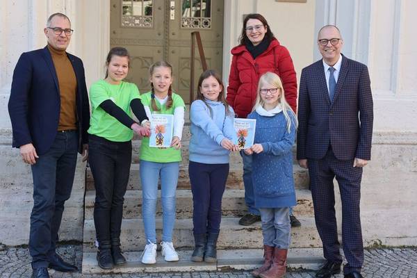 Oberbürgermeister Peter Kleine, Frida, Rebekka, Olivia, Luna, Kinder- und Jugendbeauftragte Sina Solaß und Bürgermeister Ralf Kirsten zeigen den Rathausführer